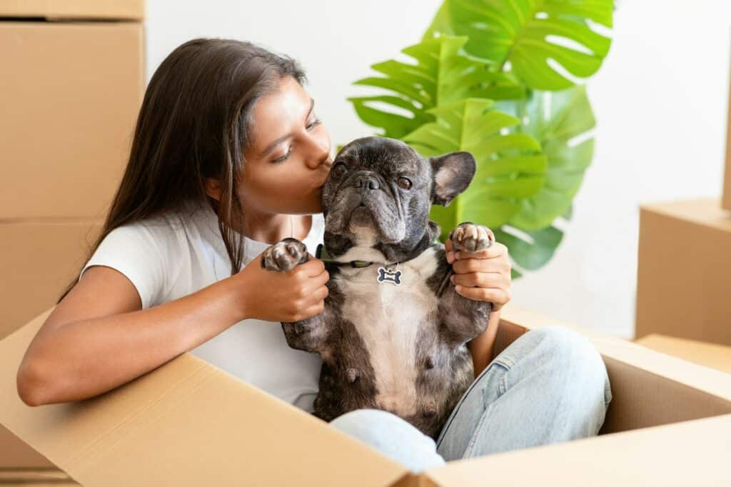 Happy lady moving to new apartment, kissing her cute pet