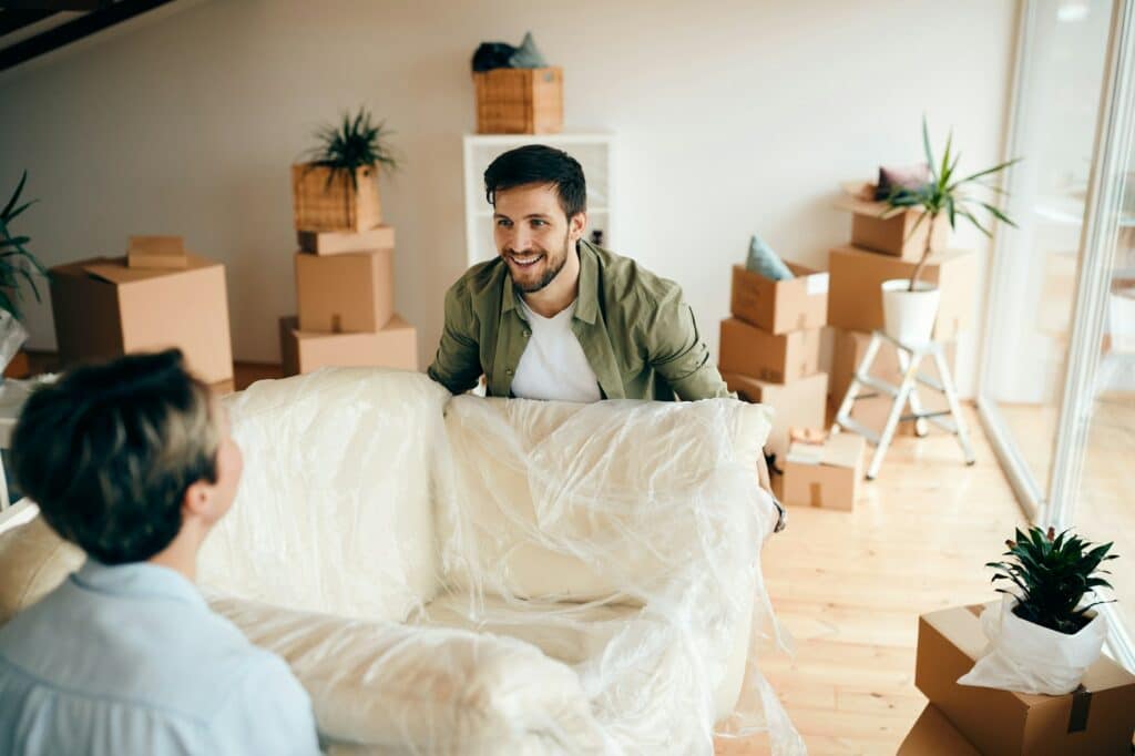 Happy couple carrying furniture into their new apartment.