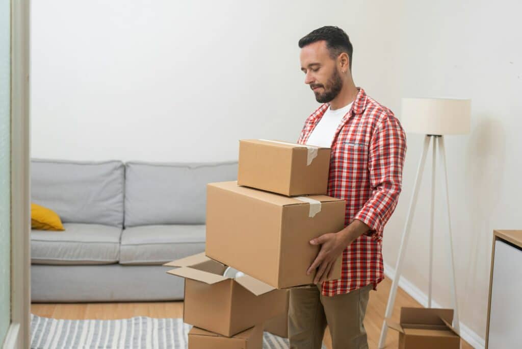 Serious male plans to move holding cardboard boxes