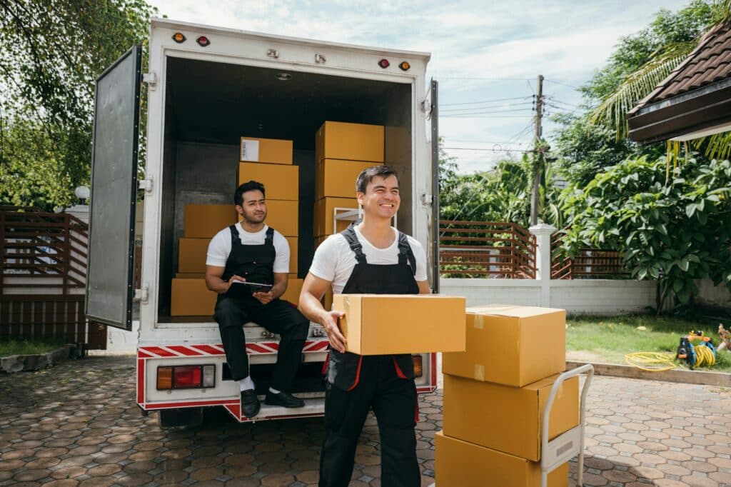 Moving service workers unload boxes from a van showing teamwork and cooperation. Delivery men in